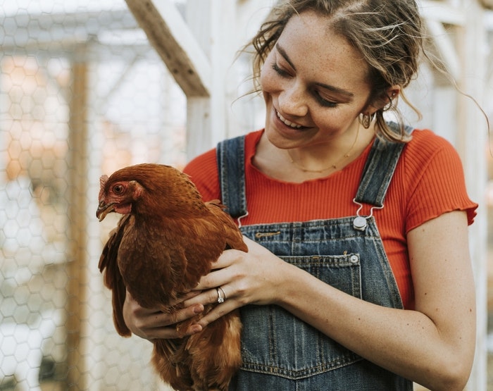 woman-with-red-shirt-holding-a-brown-hen